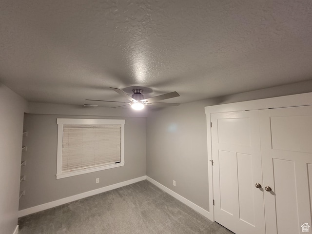 spare room with a textured ceiling, baseboards, a ceiling fan, and carpet