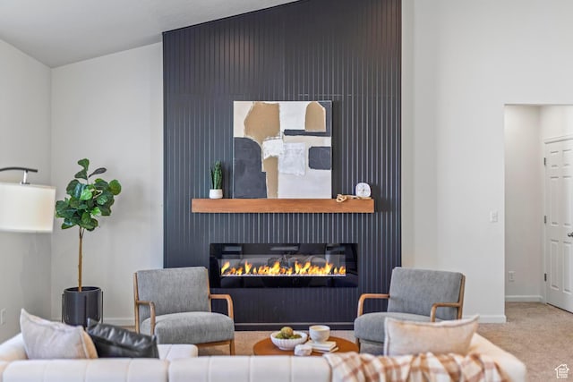 living room featuring baseboards, a glass covered fireplace, and carpet floors