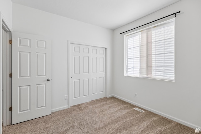 unfurnished bedroom featuring a closet, visible vents, baseboards, and carpet