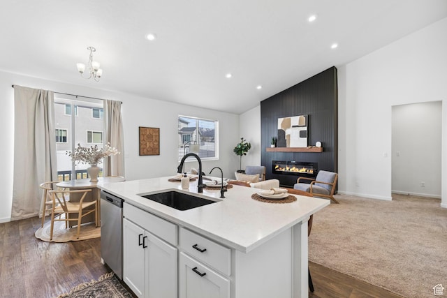 kitchen with stainless steel dishwasher, a sink, open floor plan, a notable chandelier, and plenty of natural light