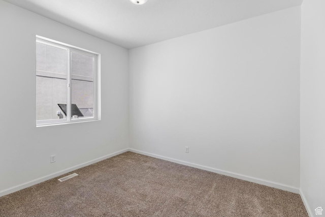 spare room with carpet, visible vents, and baseboards