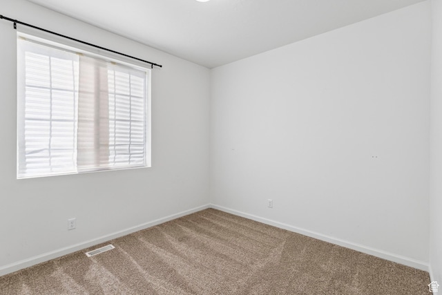 carpeted empty room with visible vents and baseboards