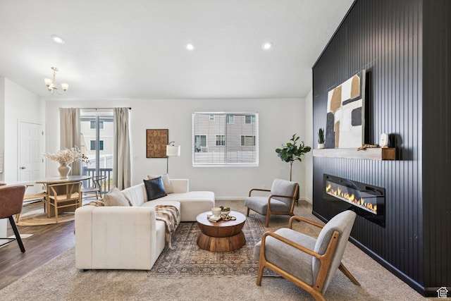living room with a glass covered fireplace, recessed lighting, a chandelier, wood finished floors, and baseboards
