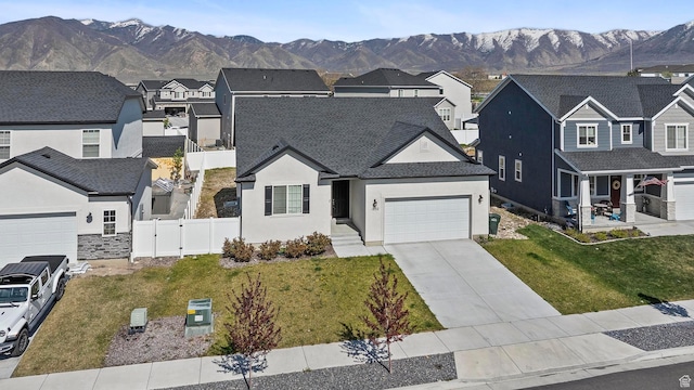 view of front of property featuring a garage, stucco siding, fence, a mountain view, and a residential view