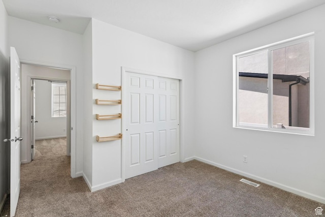 unfurnished bedroom featuring carpet floors, baseboards, a closet, and visible vents