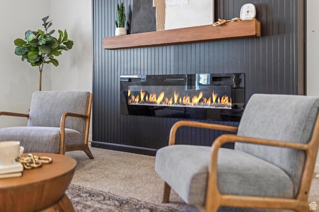sitting room featuring a lit fireplace and carpet floors