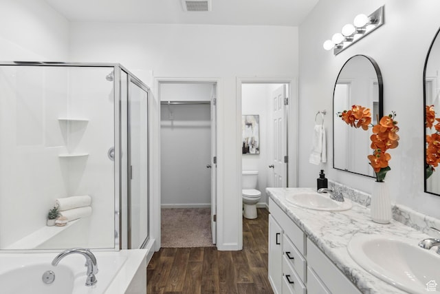 bathroom featuring a shower stall, wood finished floors, a sink, and toilet