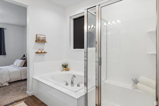 bathroom featuring a shower stall, a garden tub, wood finished floors, and ensuite bath