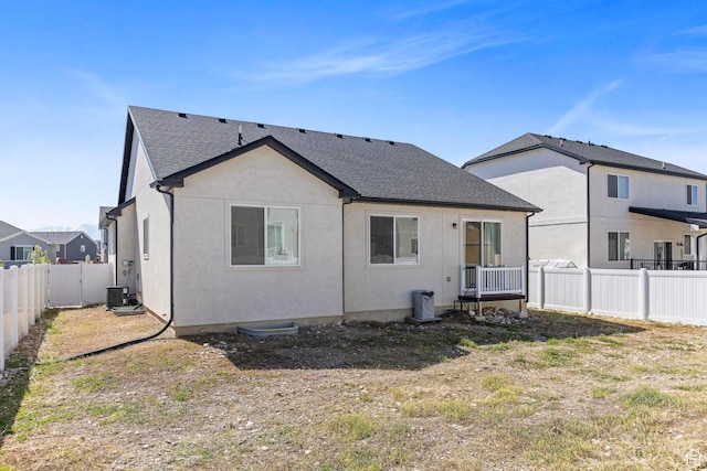 back of property featuring a shingled roof, a fenced backyard, stucco siding, and central AC unit
