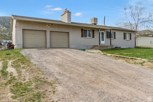 ranch-style house with a garage, central air condition unit, brick siding, a chimney, and driveway