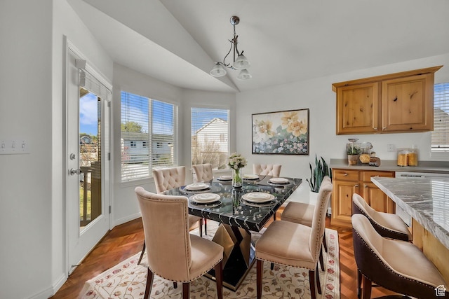 dining space featuring baseboards, wood finished floors, a notable chandelier, and vaulted ceiling
