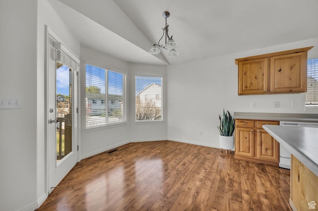 unfurnished dining area featuring wood finished floors, an inviting chandelier, baseboards, and lofted ceiling