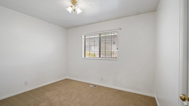 carpeted empty room with visible vents, baseboards, and a textured ceiling
