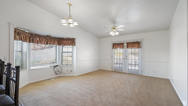 carpeted empty room featuring ceiling fan with notable chandelier, baseboards, vaulted ceiling, and visible vents