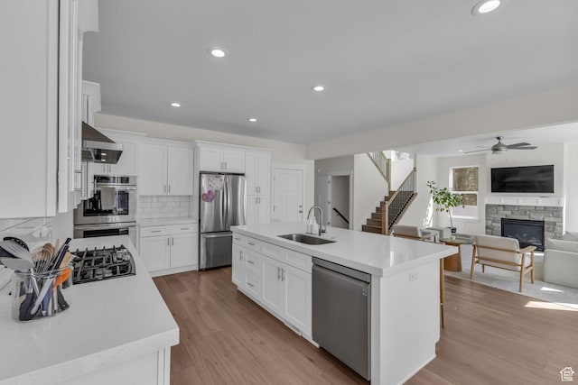 1958 E Janet Kay Ln, Holladay, UT 84121 - kitchen with wall chimney exhaust hood, a sink, a stone fireplace, appliances with stainless steel finishes, and ceiling fan