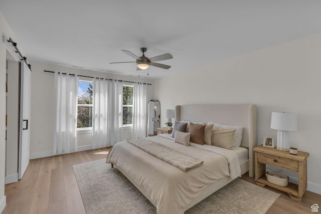 1958 E Janet Kay Ln, Holladay, UT 84121 - bedroom featuring a barn door, light wood-style flooring, and baseboards
