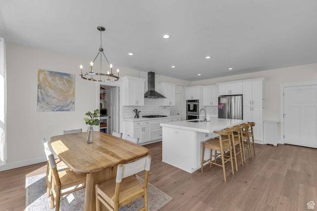 1958 E Janet Kay Ln, Holladay, UT 84121 - kitchen featuring an inviting chandelier, wall chimney range hood, a sink, stainless steel appliances, and decorative backsplash