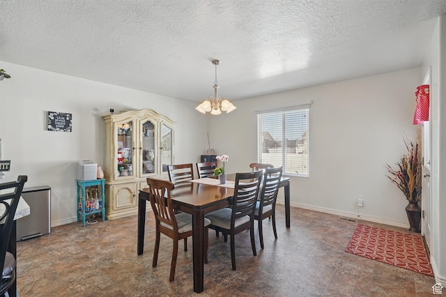 dining area with baseboards, a notable chandelier, and a textured ceiling