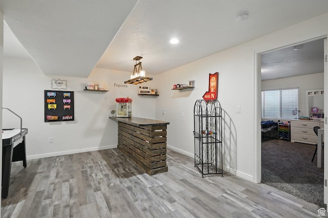 interior space with wine cooler, baseboards, a bar, and wood finished floors