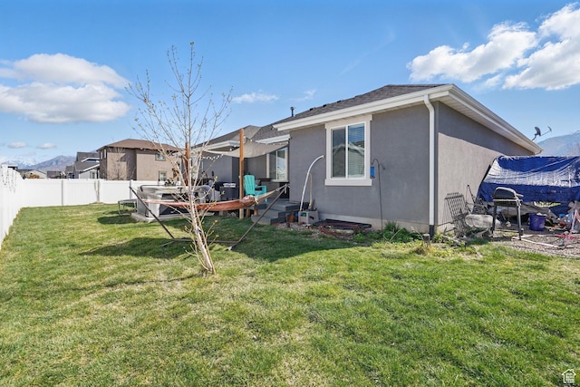 back of property featuring a yard, a fenced backyard, and stucco siding