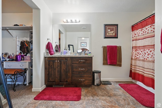 full bathroom featuring stone finish floor, vanity, and baseboards
