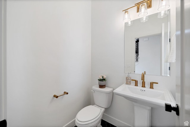half bath featuring baseboards, a sink, and toilet