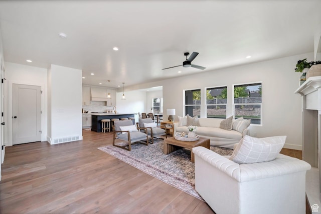 living room featuring recessed lighting, ceiling fan, visible vents, and light wood-style floors