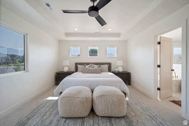 carpeted bedroom with baseboards, a ceiling fan, a tray ceiling, and visible vents