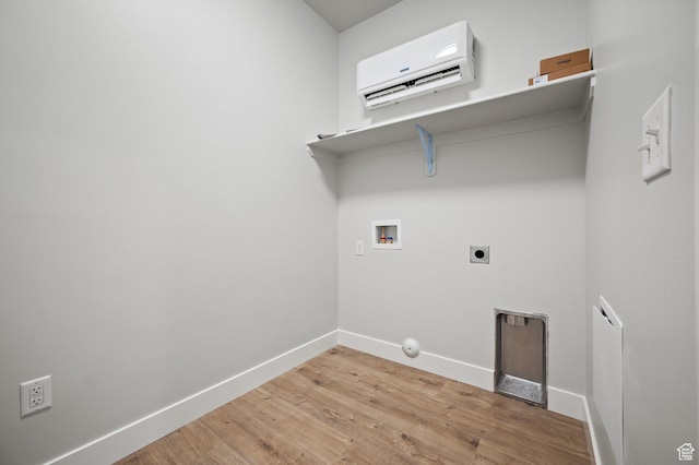clothes washing area featuring baseboards, an AC wall unit, laundry area, light wood finished floors, and hookup for a washing machine