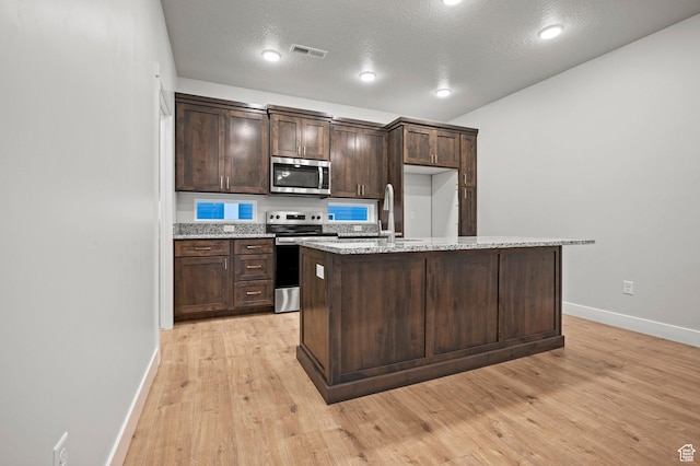 kitchen with dark brown cabinetry, baseboards, visible vents, appliances with stainless steel finishes, and a sink