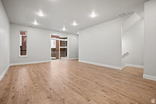 unfurnished living room featuring visible vents, baseboards, and light wood-style flooring