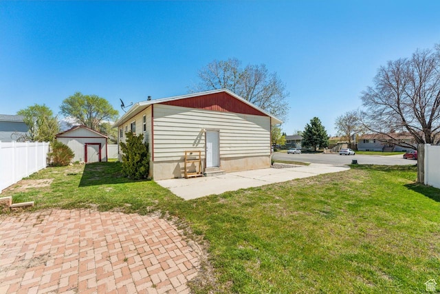 rear view of property featuring a yard, a storage unit, fence, and an outbuilding