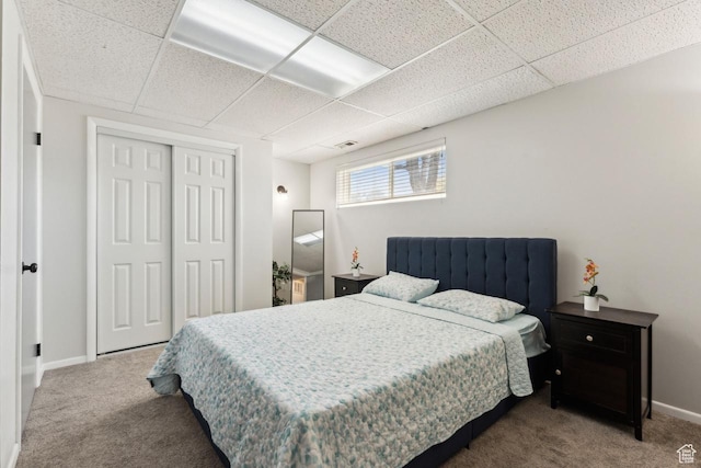 carpeted bedroom with a closet, baseboards, a paneled ceiling, and visible vents