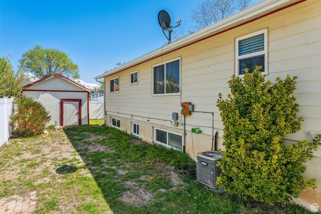rear view of property featuring a shed, central AC, an outdoor structure, and fence