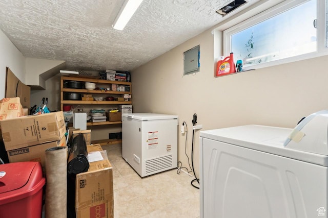 laundry room with separate washer and dryer, laundry area, a textured ceiling, and light tile patterned flooring