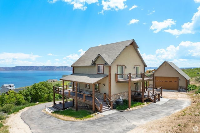 679 N Cambry Dr, Garden City, UT 84028 - view of front of home featuring stone siding, stucco siding, a balcony, roof with shingles, and a garage