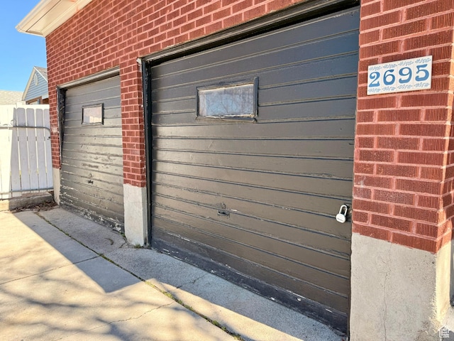 exterior space featuring fence, brick siding, and a garage