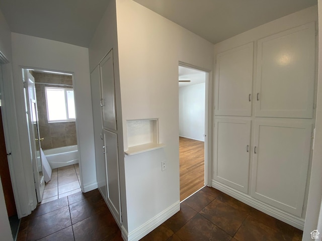 hall featuring dark tile patterned flooring and baseboards