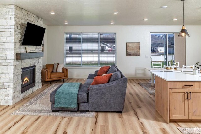 585 S 400 E, Hyrum, UT 84319 - living room featuring a stone fireplace, light wood finished floors, baseboards, and recessed lighting