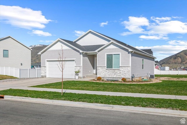 585 S 400 E, Hyrum, UT 84319 - view of front of property featuring an attached garage, driveway, stone siding, a mountain view, and central air condition unit