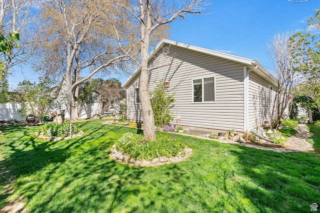 view of home's exterior featuring fence and a lawn