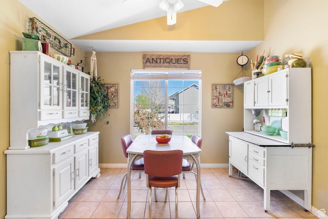 dining room featuring light tile patterned floors, baseboards, a ceiling fan, and lofted ceiling