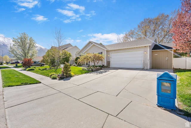 view of front of home with driveway, a garage, fence, and a front lawn