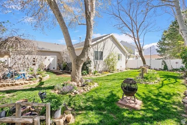 exterior space featuring fence, a fire pit, and a lawn