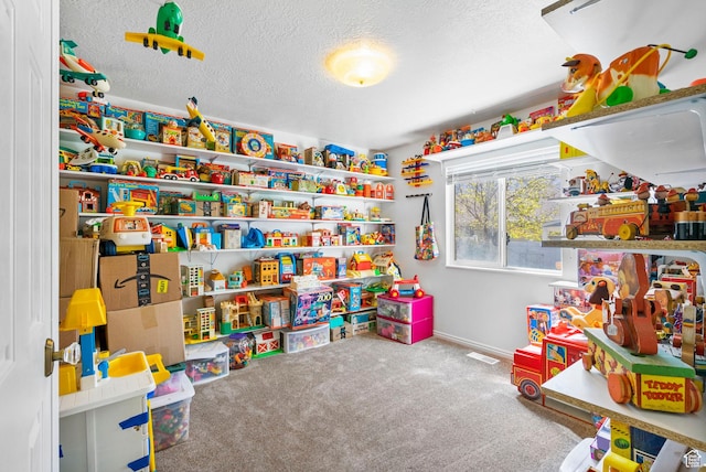 playroom with carpet, a textured ceiling, and baseboards
