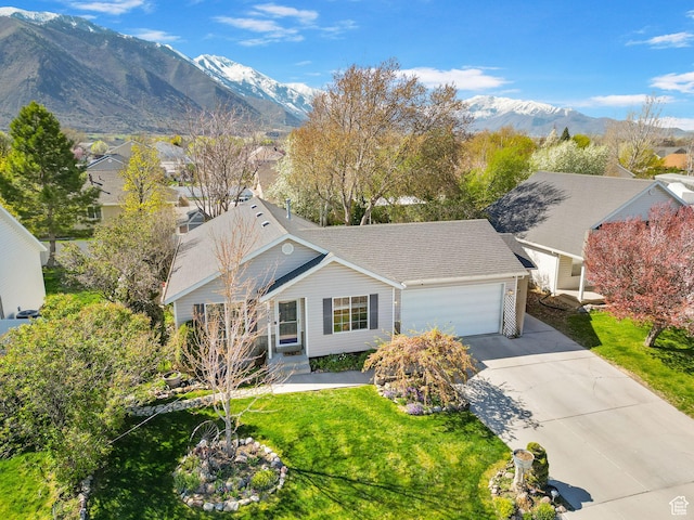 view of front of house with concrete driveway, a mountain view, a front lawn, and a garage