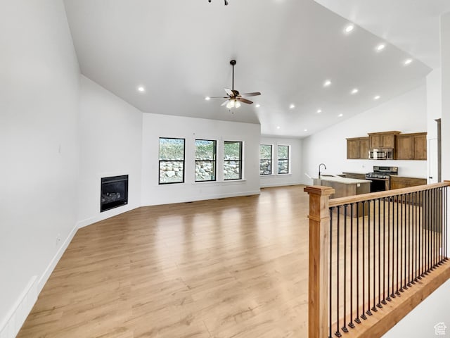 unfurnished living room with light wood-style floors, ceiling fan, a glass covered fireplace, vaulted ceiling, and recessed lighting