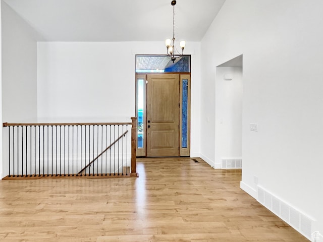 foyer entrance featuring baseboards, visible vents, light wood-type flooring, and an inviting chandelier