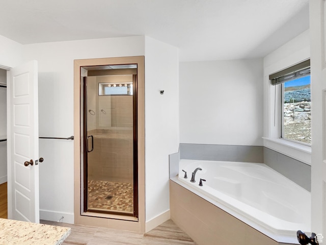 full bathroom with baseboards, a shower stall, wood finished floors, and a garden tub