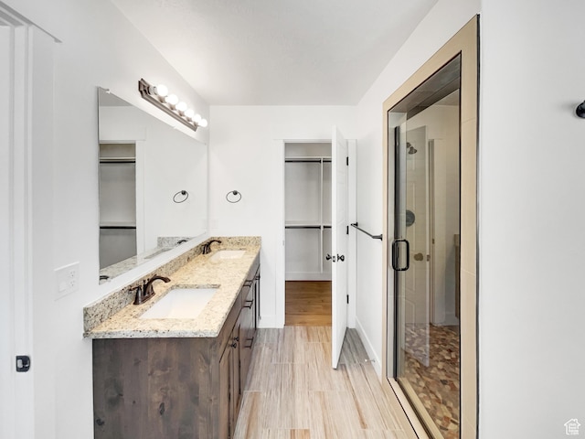full bath with a sink, a walk in closet, and a shower stall